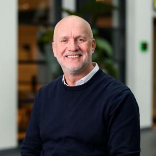a man in a blue sweater and a bald head smiling